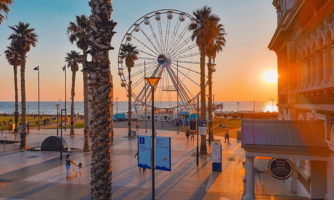 Sunset at Glenelg Beach boardwalk area with a ferris wheel and tall palm trees