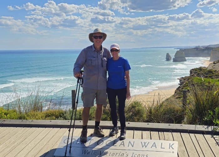 Scenic coastal walk along the Great Ocean Road with two hikers enjoying ocean views and limestone fo.