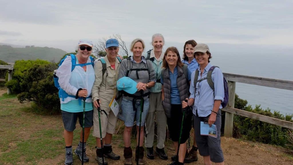 Enjoying a group walk along the scenic coastal trail with friends in outdoor gear.