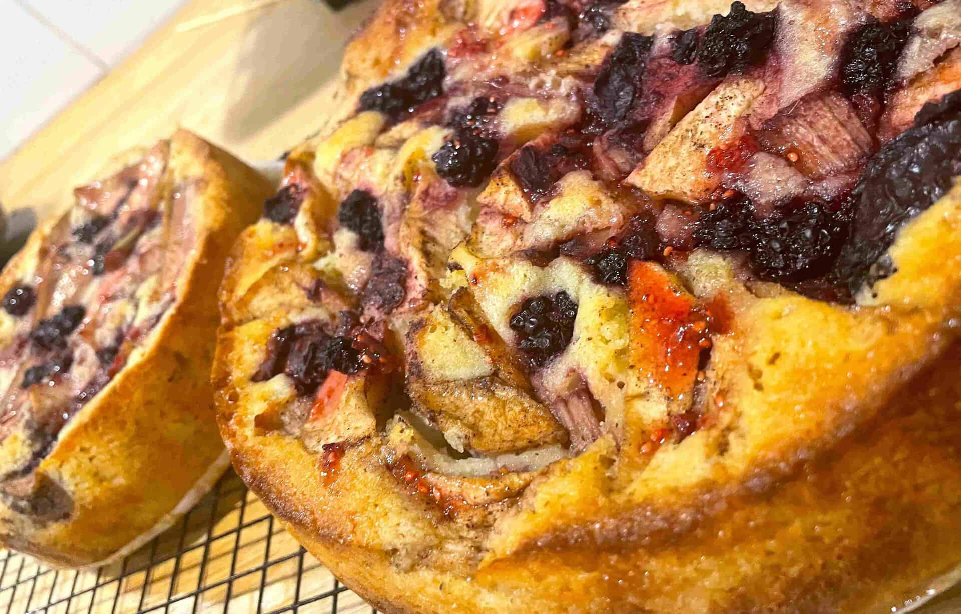 Two round fruit-studded cakes cool on a wire rack, featuring a golden-brown crust with visible pieces of plum and apple on top—perfect for enjoying as sustainable food on the Great Ocean Walk.